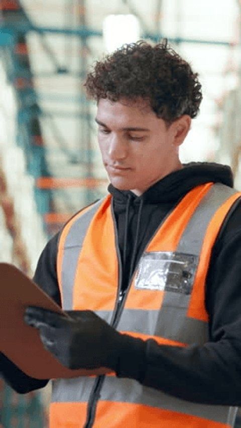 Mitarbeiter in Warnweste prüft mit Handschuhen eine Mappe an Bord